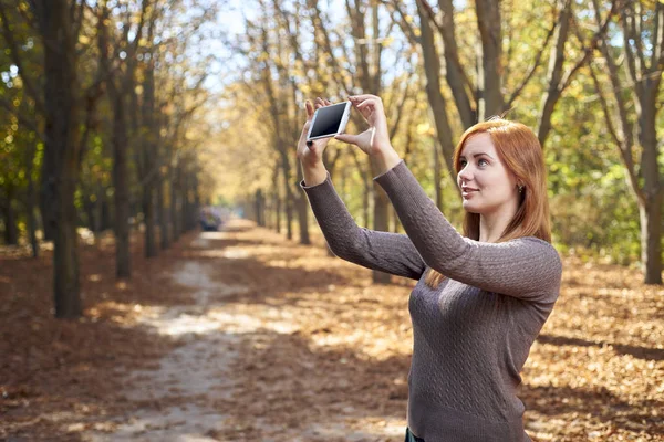 Beautiful girl takes pictures of herself on the phone — Stock Photo, Image