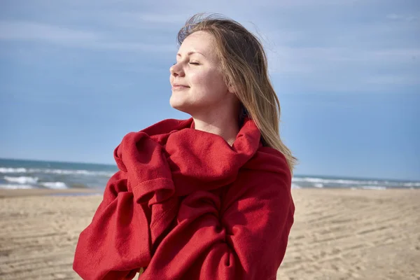 Frau lächelt, während sie an einem einsamen Strand steht — Stockfoto