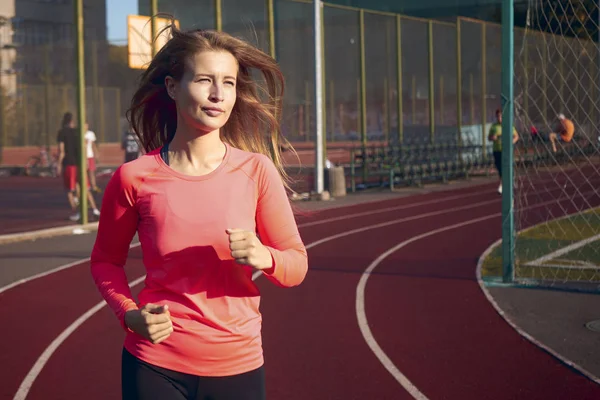 Una mujer corre por un estadio por la mañana —  Fotos de Stock