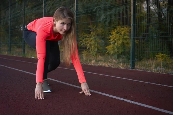 Mujer atlética se para en una cinta de correr en un estadio y está listo t —  Fotos de Stock