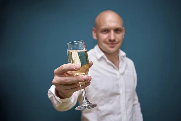 Bel homme se tient debout avec une coupe de champagne contre un mur bleu — Photo