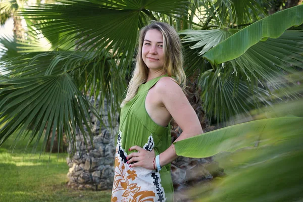 Belle femme se tient sur un fond de palmiers verts — Photo