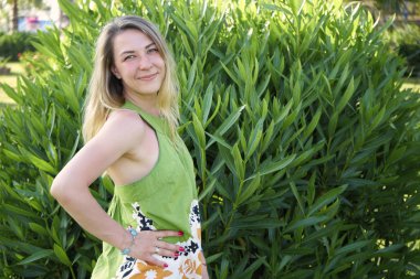 Güzel bir kadın bitkilerin arka planında duruyor.