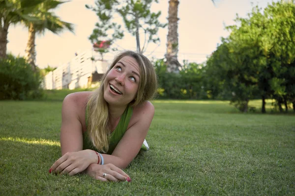 Woman looks up while lying on a green lawn — Stock Photo, Image