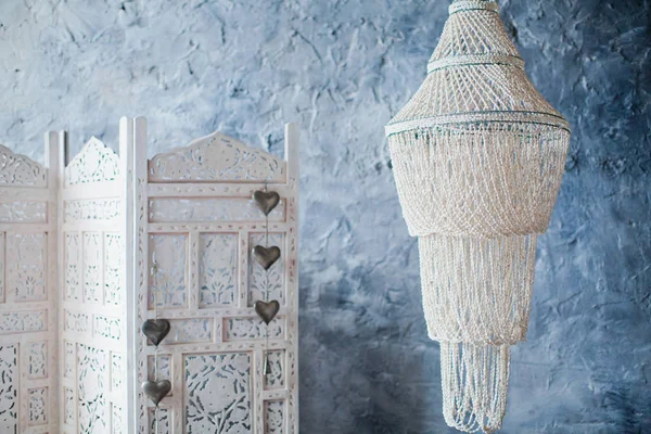white folding screen and chandelier of shells