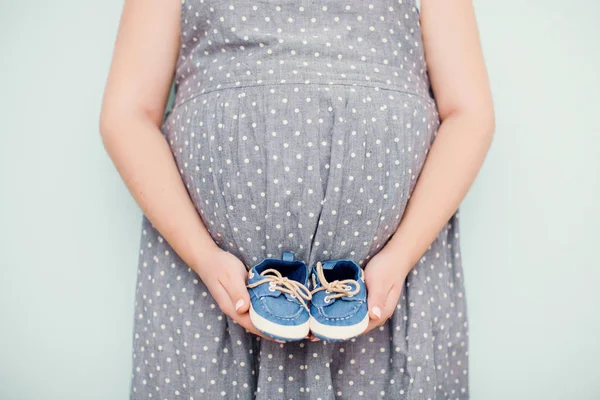 Mujer embarazada con zapatos de bebé pequeños —  Fotos de Stock