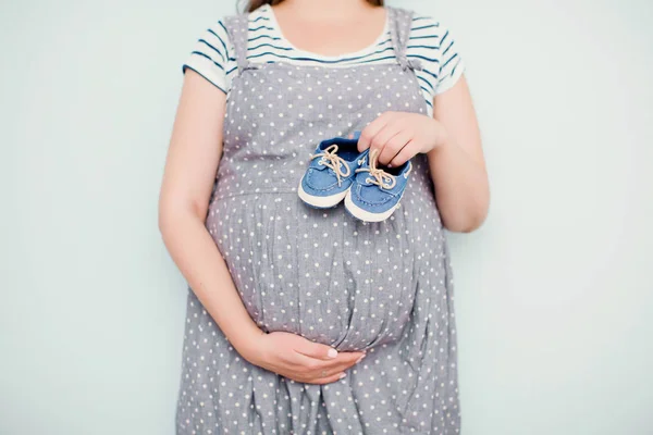 Mujer embarazada con zapatos de bebé pequeños — Foto de Stock