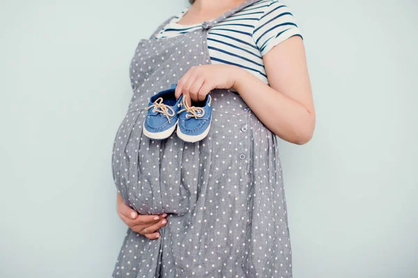 Mujer embarazada con zapatos de bebé pequeños — Foto de Stock