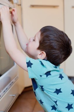 Küçük çocuk fırının yanında elmalı turta bekliyor. Küçük çocuk mutfakta pasta bekliyor.