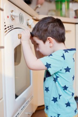 Küçük çocuk fırının yanında elmalı turta bekliyor. Küçük çocuk mutfakta pasta bekliyor.