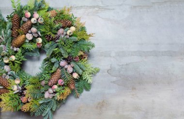 Çelenkli Noel afişi. Çam kozalaklı Noel çelengi, böğürtlen, elma, fındık ve yeşil yapraklı hafif grunge arka planda