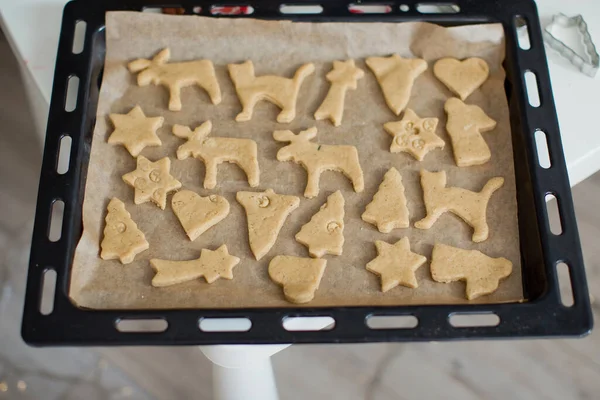 Christmas baking background: dough, cookie cutters, spices and Christmas decorations. Christmas cookies on a black baking tray