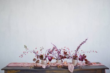 Pembe peçeteler, pembe koşucular, altın çatallar ve bıçaklar, mumlar ve sonbahar yaprakları ve böğürtlenlerle güzel bir masa.