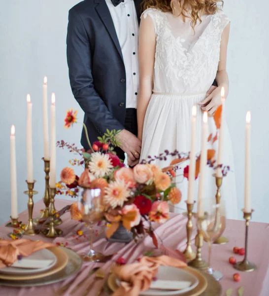 Autumn wedding concept. Bride and groom near decorated table with autumn flowers, candles and table setting