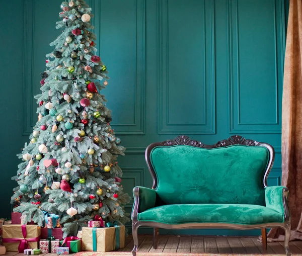 Green Christmas interior. Living room with green walls, green sofa and red, pink and gold Christmas decorations on Christmas tree