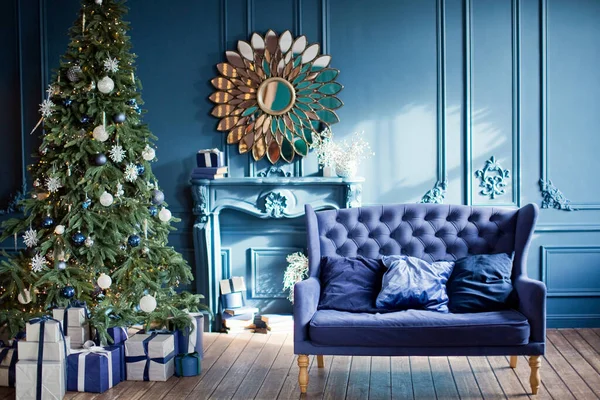 Mavi ve gümüş renkli Noel içleri. Mavi duvarlı oturma odası, mavi kanepe, gümüş ve mavi Noel süslemeleri Noel ağacında