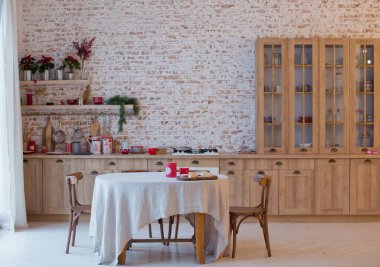 Tuğladan duvarları, kırmızı Noel süslemeleri ve ışıkları olan aydınlık mutfak.