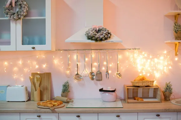 Light kitchen with Christmas decorations and lights. White furniture kitchen with pink and blue chairs and utensils