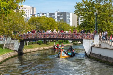 Aveiro, Portekiz: 10 Ağustos 2019 - Köprüde yürüyen bir sürü insan ve altından geçen geleneksel teknelerle dolu bir gün