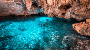 Gökkuşağı cenote ve turuncu kayalıklarda kristal mavi su