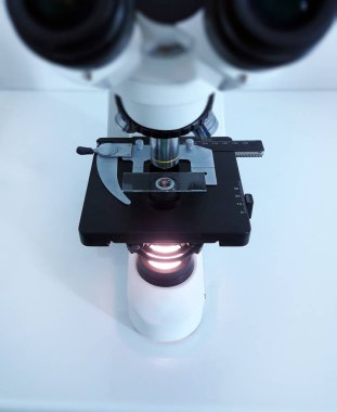 Laboratuvarda metal mercekle mikroskobun yakın çekim görüntüsü.