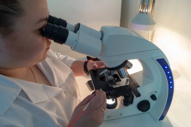 Laboratuardaki kız mikroskopla çalışıyor.