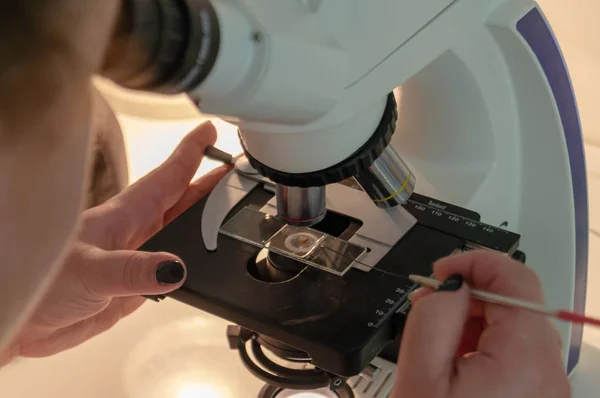 The girl in the lab works with a microscope