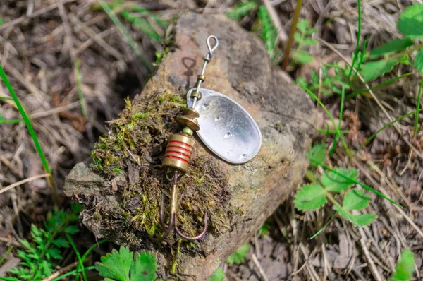 Accesorios de pesca. Bocetos y señuelos que yacen sobre una piedra con un fondo forestal —  Fotos de Stock