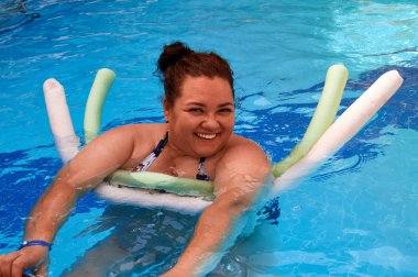 mutlu kız bir köpük sopa kullanarak, bir havuzda yüzer