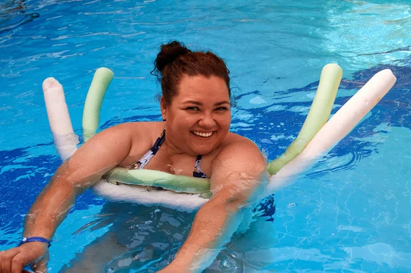 mutlu kız bir köpük sopa kullanarak, bir havuzda yüzer