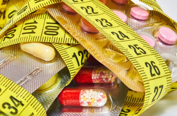 Pillole con nastro di misurazione, rappresentano l'industria pillola di dieta. Concetto di farmaci dietetici — Foto Stock