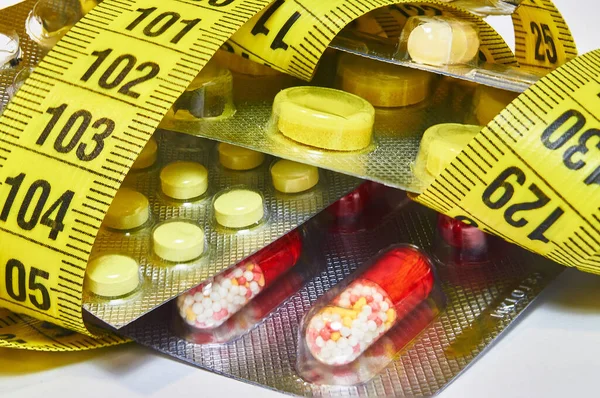 Ölçüm bandı olan haplar diyet hapı endüstrisini temsil ediyor. Diyet ilaçları konsepti