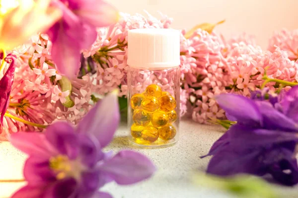 A jar with fish oil capsules and purple liliac flowers — Stock Photo, Image