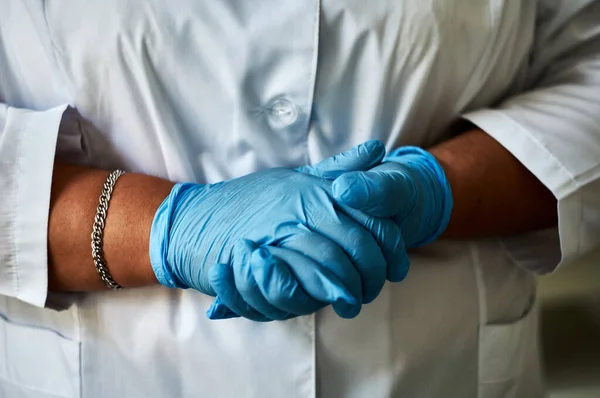 Laboratuvar önlüğü ve tıbbi eldiven giymiş bir kızın elleri..