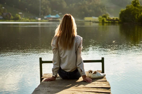 Nehrin arka planında bir kayanın üzerinde oturan arka plandaki kadın.