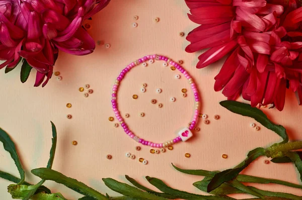 Handmade beadwork, beading as a hobby. Decorations made with your own hands on the background of various flowers and plants.