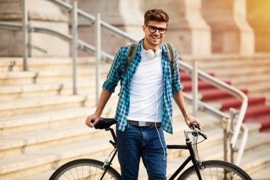 gözlük ve sokağın Üniversitesi önünde bisikletiyle üzerinde bisiklet duran genç öğrenci