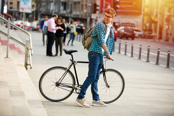 young student with glasses on the street in front of university or high school, leving with his bicycle home