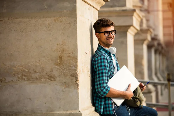 Усміхнений Молодий Студент Окулярах Рюкзаку Спираючись Своїм Ноутбуком Руках Кольмені — стокове фото