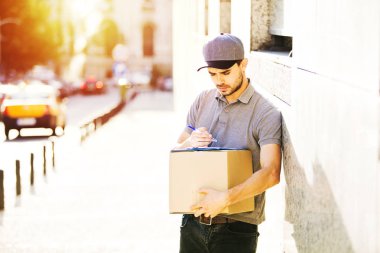 Senin nakliye işte. sokakta bir yerde onun kollarında parsel olması onun teslim formu, notlar odaklı kurye