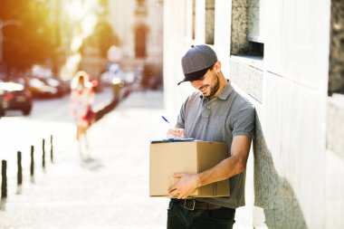 Senin nakliye işte. sokakta bir yerde onun kollarında parsel olması onun teslim formu, notlar odaklı kurye
