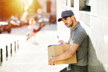Senin nakliye işte. sokakta bir yerde onun kollarında parsel olması onun teslim formu, notlar odaklı kurye