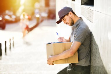 Senin nakliye işte. sokakta bir yerde onun kollarında parsel olması onun teslim formu, notlar odaklı kurye