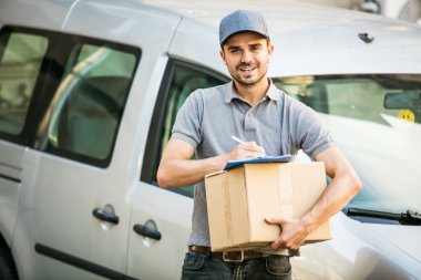 Senin nakliye işte. Onun karton ile kap ayakta ile gri tişörtlü adam genç teslimat kutusu formunu teslim, arabasının önünde sokakta istemcinin, dışarıda tanışmaya hazır için