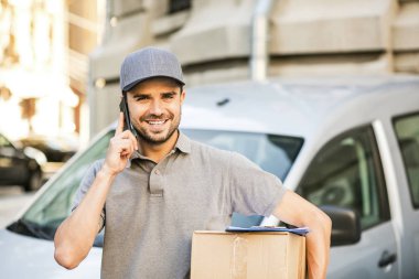 Senin nakliye işte. paketi teslim etmesi için istemci arama sokakta onun karton kutu ile kap ayakta ile gri tişörtlü teslimat adam