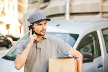 Senin nakliye işte. paketi teslim etmesi için istemci arama sokakta onun karton kutu ile kap ayakta ile gri tişörtlü teslimat adam