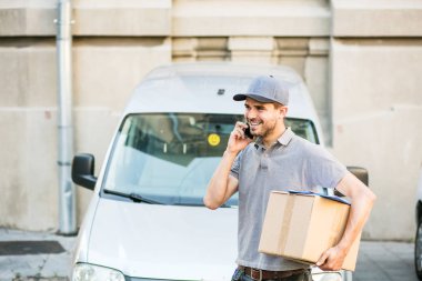 Senin nakliye işte. paketi teslim etmesi için istemci arama sokakta onun karton kutu ile kap ayakta ile gri tişörtlü teslimat adam