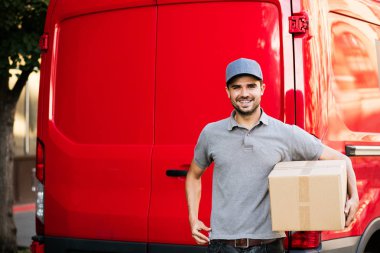 Senin nakliye işte. teslimatçı arabasını paket istemciye, dışarıda sokakta vermeye hazır arkasında onun karton kutu ile kap ayakta ile gri gömlek