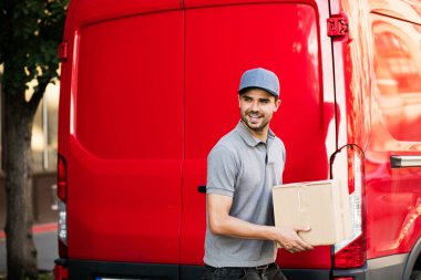 Senin nakliye işte. teslimatçı arabasını paket istemciye, dışarıda sokakta vermeye hazır arkasında onun karton kutu ile kap ayakta ile gri gömlek