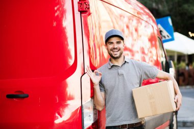 Senin nakliye işte. arabasını, paketin istemciye, dışarıda sokakta, vermeye hazır arkasında onun karton kutu ile kap ayakta ile gri tişörtlü teslimat adam güven ve ok işareti gösteren
